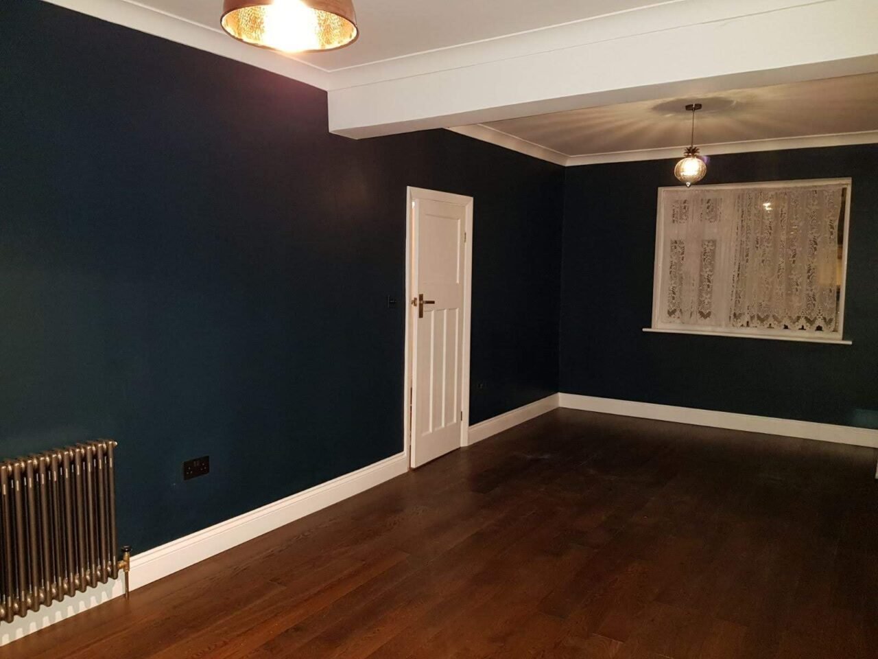 Renovated reception room in Walthamstow with dark walls, white joinery and a stained board floor