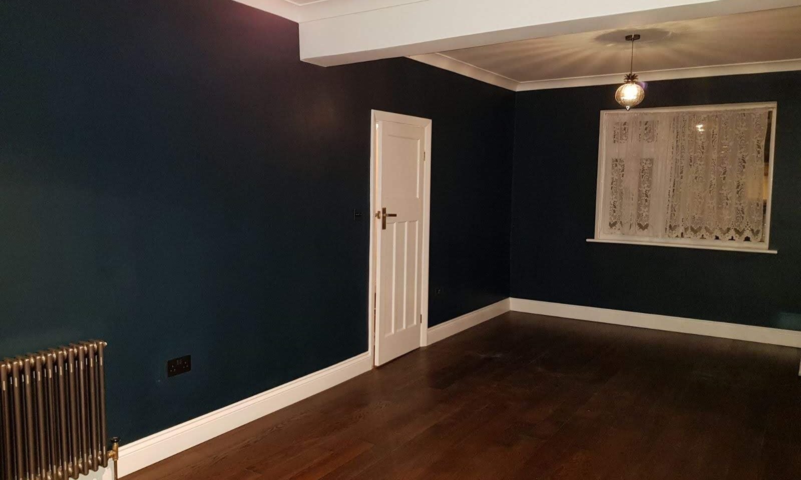 Renovated reception room in Walthamstow with dark walls, white joinery and a stained board floor