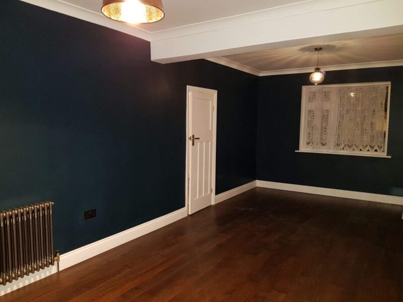Renovated reception room in Walthamstow with dark walls, white joinery and a stained board floor